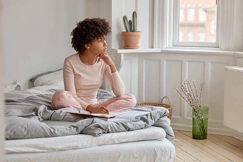 woman sitting on a bed looking off to the side